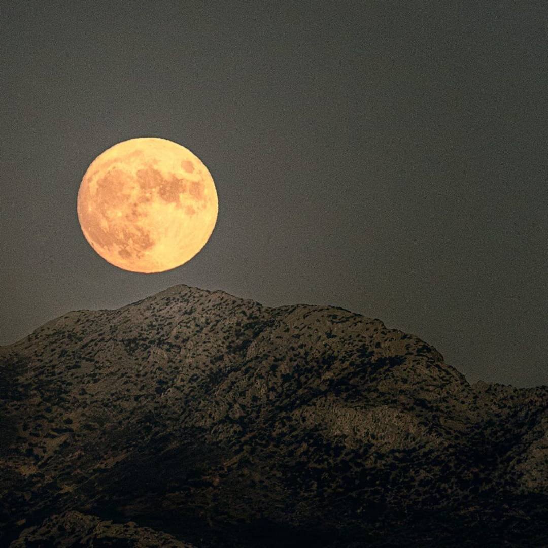 living inquiry by tomm claude. ein großer goldener vollmond geht hinter einer in grün gehaltenen bergkette auf. ein mystischer Moment, der spirituelles Coaching und Zen-Meditation für emotionale Heilung und Embodiment widerspiegelt.