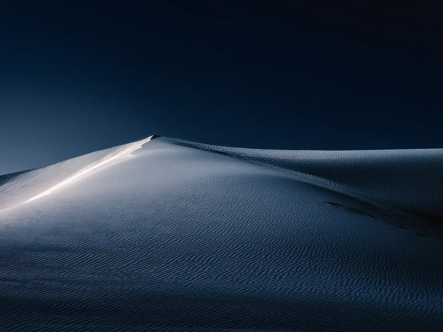 spirituelles coaching und zen meditation für emotionale heilung und embodiment Wogende Sanddünen unter einem dunklen, tiefblauen Himmel bei Nacht. Das weiche Mondlicht wirft sanfte Schatten und fördert ein Gefühl von Heilung und Ruhe, das die Gelassenheit des spirituellen Coachings widerspiegelt.