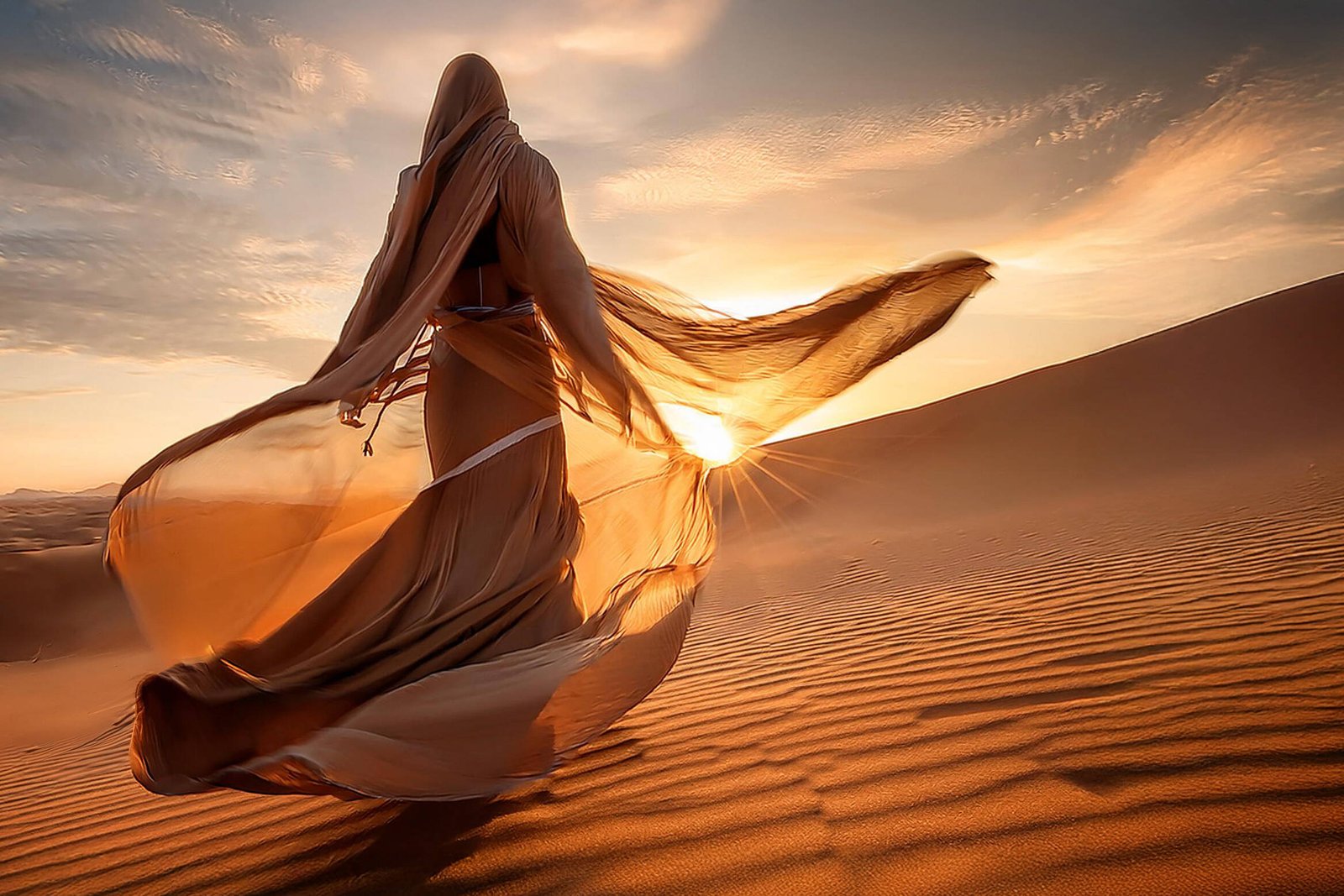 spirituelles coaching und zen meditation für emotionale heilung und embodiment Eine in fließenden, durchscheinenden Stoff gehüllte Person läuft bei Sonnenuntergang über Sanddünen, wobei das Sonnenlicht die Figur beleuchtet und lange Schatten auf die gewellte Wüstenlandschaft wirft.