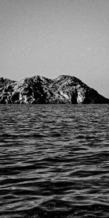 living inquiry by tomm claude Eine lächelnde Frau steht hüfttief im Meer und hält spielerisch ein Kleidungsstück hoch, während sie in die Kamera schaut. Sie verkörpert innere Ruhe und Freude daran, im Hier und Jetzt zu sein, während sich hinter ihr der Himmel und der Horizont erstrecken. spirituelles coaching und zen meditation für emotionale heilung, erwachen und essenz